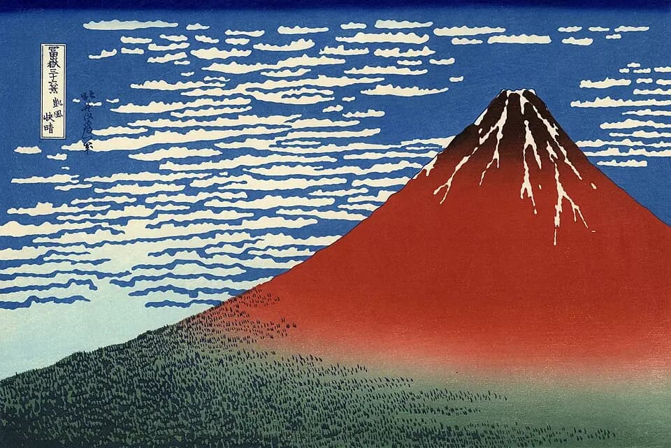 Góra Fuji świecąca na czerwono pod błękitnym, pełnym chmur niebem w Czerwonej Fuji w Hokusai