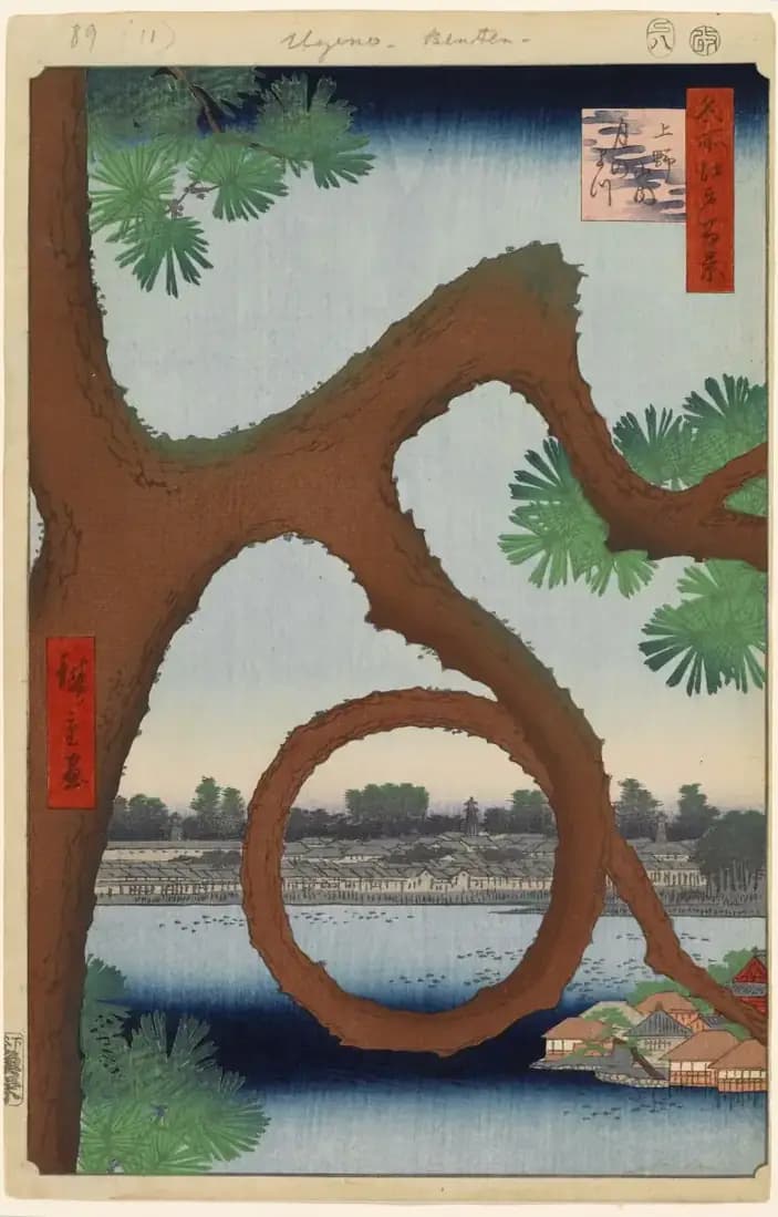 A circular pine branch frames a distant temple building across the landscape at Ueno